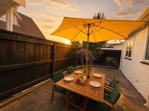 a wooden table with a yellow umbrella on a patio at Maison Millie - Central Pet-Friendly Sleeps 4 in Rotorua