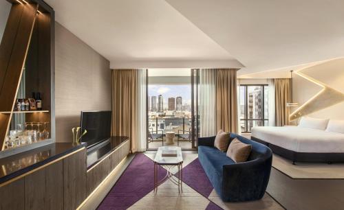 a hotel room with a bed and a couch and a tv at The Alva Hotel Brisbane, Vignette Collection by IHG in Brisbane