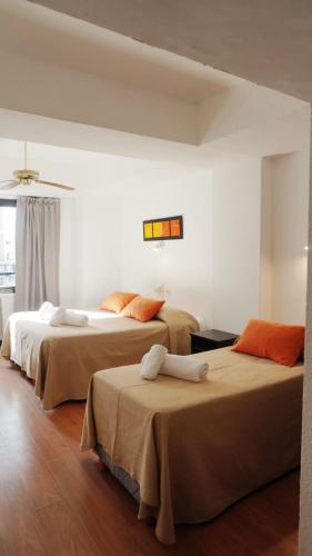 two beds in a room with white walls at Hotel Rivoli in Mar del Plata