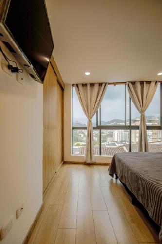 a bedroom with a bed and a large window at HOSTARA EDIFICIO CAPITALIA, El Cable, Manizales in Manizales