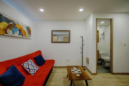 a living room with a red couch and a table at HOSTARA EDIFICIO CAPITALIA, El Cable, Manizales in Manizales