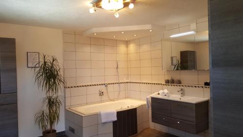 a bathroom with a tub and a sink and a mirror at Ferienhaus Stricker in Ehrwald