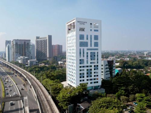a tall white building in a city with a highway at Mercure Jakarta Simatupang in Jakarta