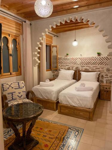 a bedroom with two beds and a table in it at Riad Nassar in Chefchaouen