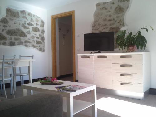 a living room with a tv on a white dresser at Albergo Diffuso Zoncolan in Ovaro