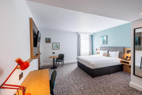 a hotel room with a bed and a desk and a table at Holiday Inn Stevenage by IHG in Stevenage