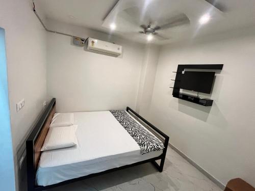 a small room with a bed and a flat screen tv at Lohith International in Shimoga