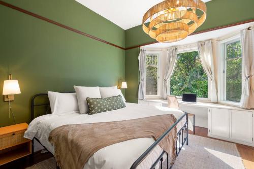 a green bedroom with a bed and a chandelier at Design-Forward | Steps to Shops & Dining | 2 Kings in Mill Valley