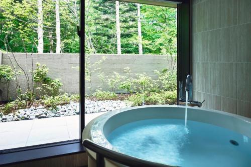a bath tub in a bathroom with a window at Hotel Indigo Karuizawa by IHG in Karuizawa