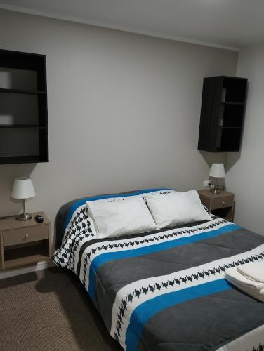 a bedroom with a bed and two night stands at cabañas los flamencos A in Punta Arenas