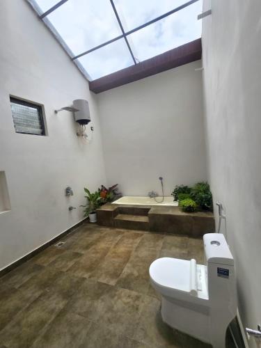 a bathroom with a toilet and a skylight at Peony By Dhiya in Jadgenhalli