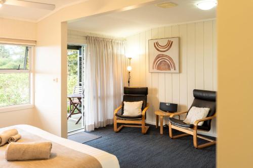 a hotel room with two chairs and a bed at Cascade Garden Apartments in Burnt Pine