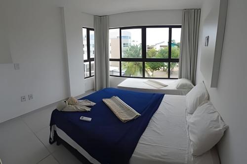 a bedroom with a bed with a blue blanket and a window at Condomínio Pérola de Porto in Ipojuca