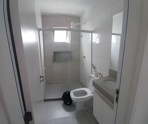 a white bathroom with a toilet and a sink at Condomínio Pérola de Porto in Ipojuca