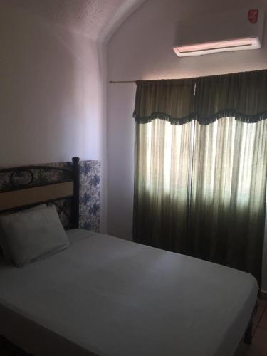 a bedroom with a bed and a window with curtains at Casa con alberca!! Ixtapa Zihuatanejo in Zihuatanejo
