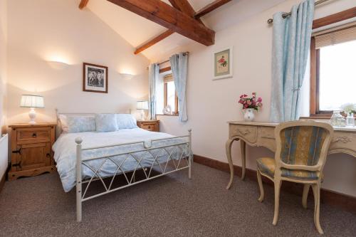 a bedroom with a bed and a desk and a chair at Skipbridge Farm Cottages in Green Hammerton