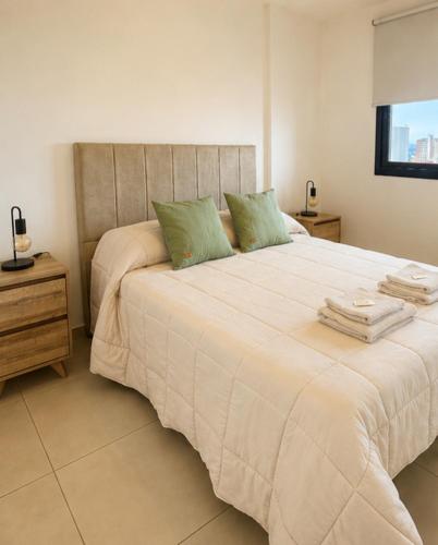 a bedroom with a large white bed with green pillows at LA RIVIERA María II - CON COCHERA in Villa María