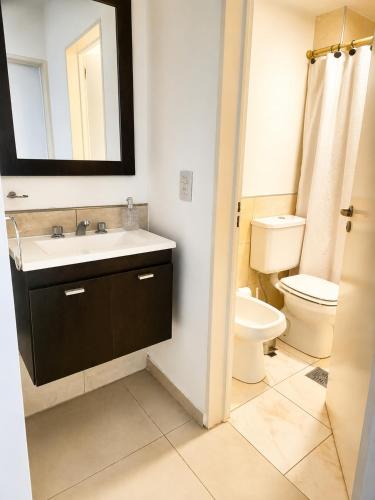 a bathroom with a sink and a toilet and a mirror at LA RIVIERA María II - CON COCHERA in Villa María
