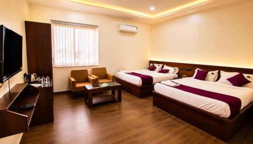 a hotel room with two beds and a flat screen tv at Hotel Lavish Grand in Tenāli