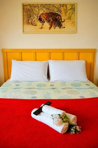 a bed with two towels on a red blanket at Refúgio do Paraty Mirim in Paraty