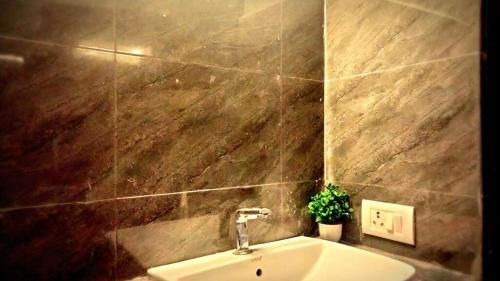 a bathroom with a sink and a tiled wall at Raj Embassy in Rudrapur
