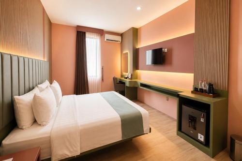 a hotel room with a bed and a television at Grand Kangen Hotel Urip Sumoharjo in Yogyakarta
