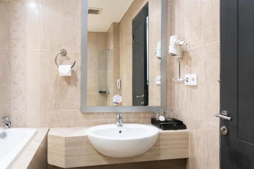 a bathroom with a white sink and a mirror at Hotel Dafam Semarang in Semarang
