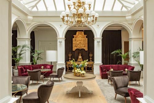 a large room with red chairs and a chandelier at Palacio de los Duques, a Gran Meliá Hotel - The Leading Hotels of the World in Madrid