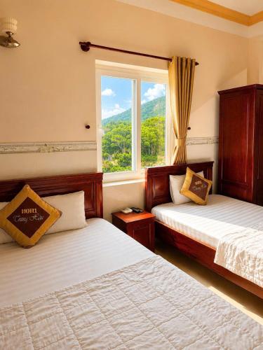 two beds in a room with a window at Trung Hậu Hotel Côn Đảo in Con Dao