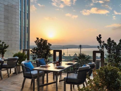 a table and chairs on a balcony with the sunset at Sofitel Abu Dhabi Corniche in Abu Dhabi