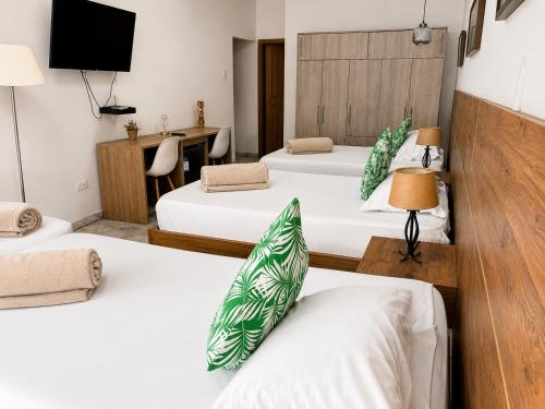 a hotel room with three beds and a tv at HOTEL BELEN-La Flora- Cali Valle del Cauca in Cali