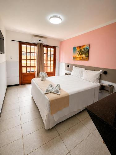 a bedroom with a large white bed and a pink wall at Pousada La Riviera - Pé na areia e Passeios em Maragogi in Maragogi