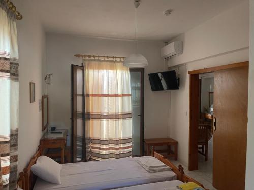 a bedroom with a bed and a television and a window at Matina's house in Samos