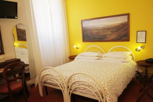 a bedroom with a white bed with a mirror at Hotel Pallotta in Assisi