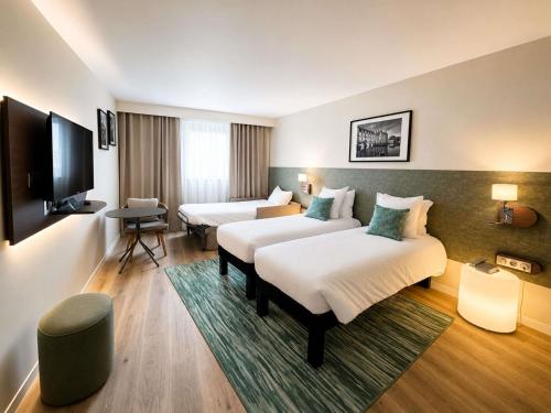 a hotel room with two beds and a flat screen tv at ibis Styles Tours Centre in Tours