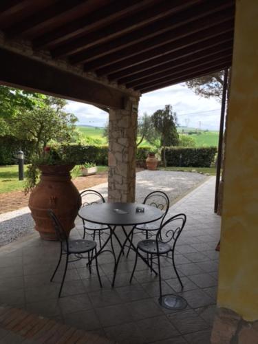 a patio with a table and chairs and a vase at Tenuta La Lupa in Castellina Marittima