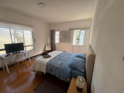 a bedroom with a bed and a desk with a computer at Alojamientos Quintamar Viña in Viña del Mar