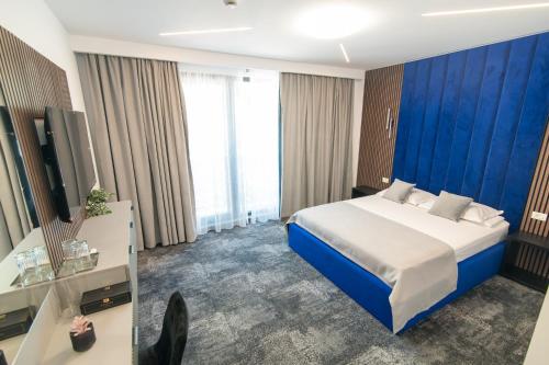 ein Hotelzimmer mit einem Bett und einer blauen Wand in der Unterkunft Simedo Boutique Hotel in Mamaia