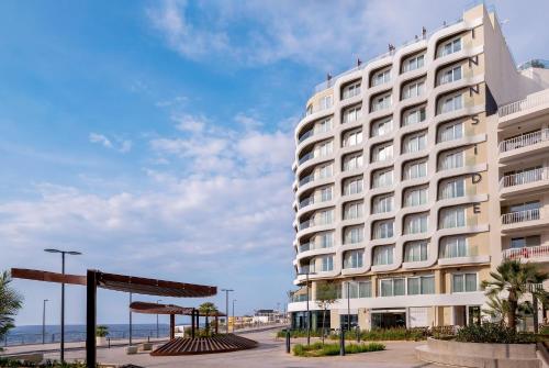 a large white building with the ocean in the background at INNSiDE by Meliá Bugibba in St. Paul's Bay