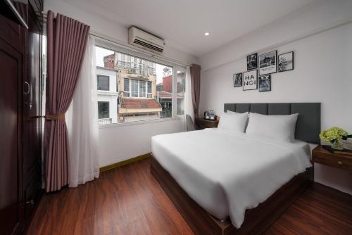 a bedroom with a large white bed and a window at TRUNG - The Coffee House in Hanoi