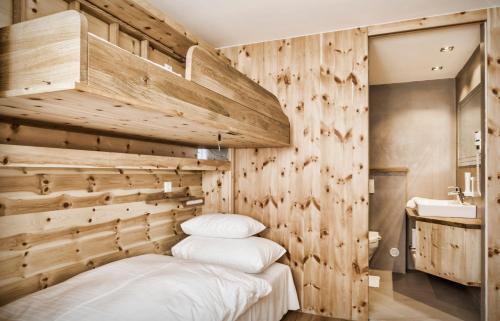 a bedroom with wooden walls and a bed with white pillows at schaus Lüftenegger - Apart-Zirbenpension in Mauterndorf