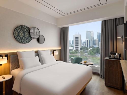 a hotel room with a bed and a large window at All Seasons Jakarta Thamrin in Jakarta