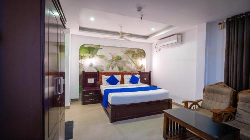 a bedroom with a king sized bed and a chair at Harshavardhana Inn in Kizhake Chālakudi