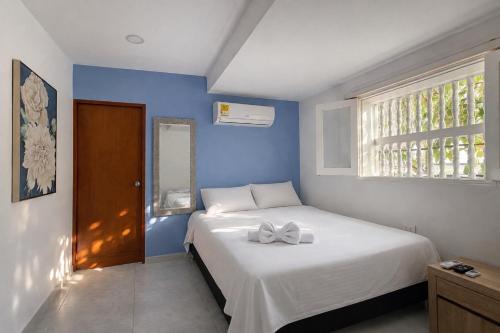 a bedroom with a white bed with a bow on it at Hotel Getsemaní Central in Cartagena de Indias