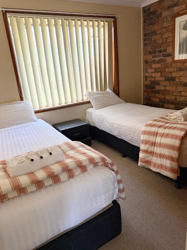 a bedroom with two beds and a window with blinds at Speers Point Serviced Apartments in Cockle Creek