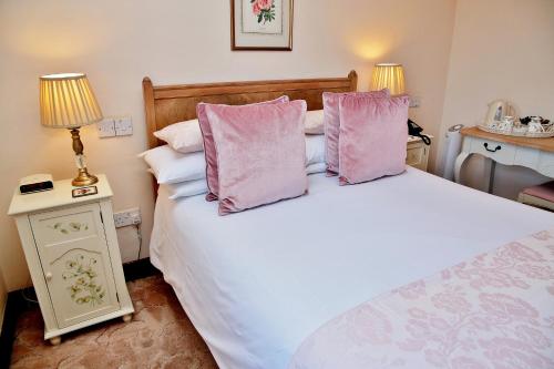 a bedroom with a large white bed with pink pillows at The Inglenook Hotel in Bognor Regis