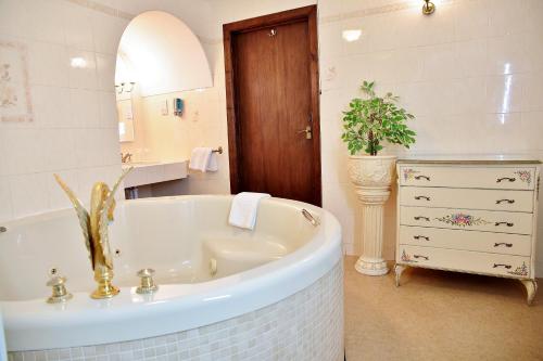 a bathroom with a tub and a sink and a mirror at The Inglenook Hotel in Bognor Regis