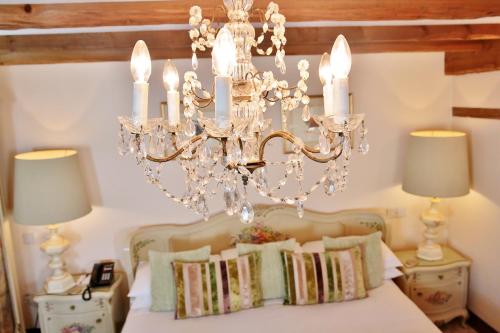 a chandelier hanging over a bed with pillows at The Inglenook Hotel in Bognor Regis