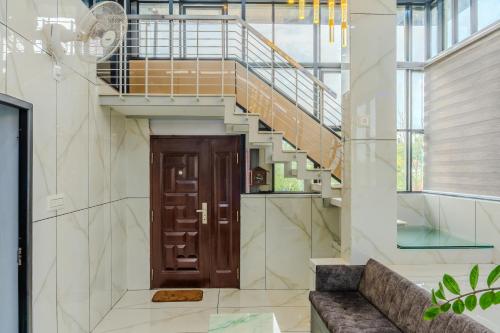 a staircase with a wooden door in a room with a couch at E7 Apartment in Bekal