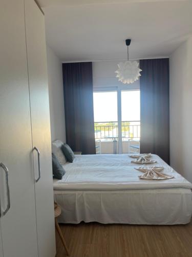 a bedroom with a large white bed with a window at Apartman Raba in Šušanj